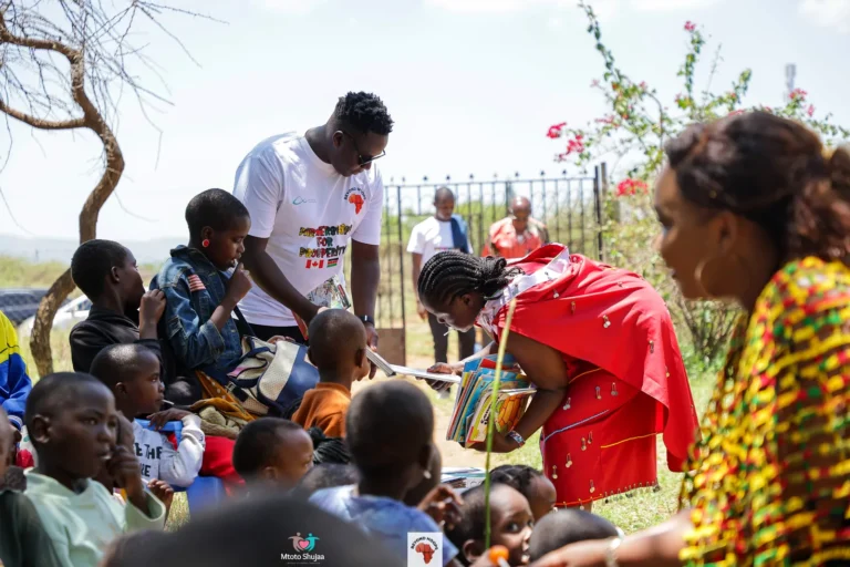 Children gather closely around volunteers reading together outdoors under the trees in Kenya