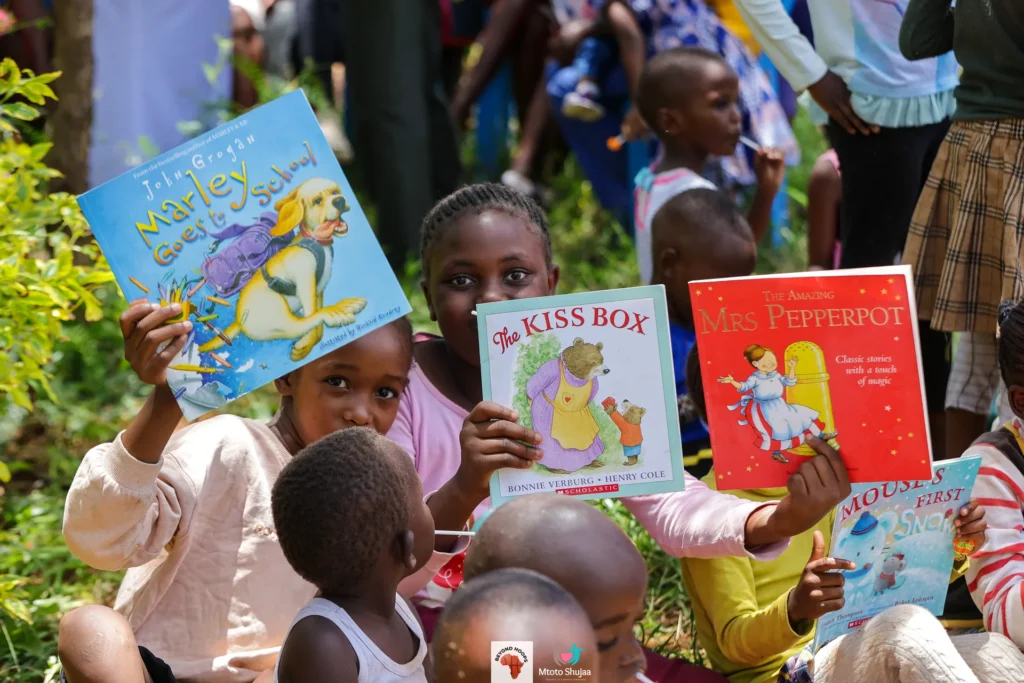 Children proudly hold up donated storybooks during a Mtoto Shujaa reading session in Kenya