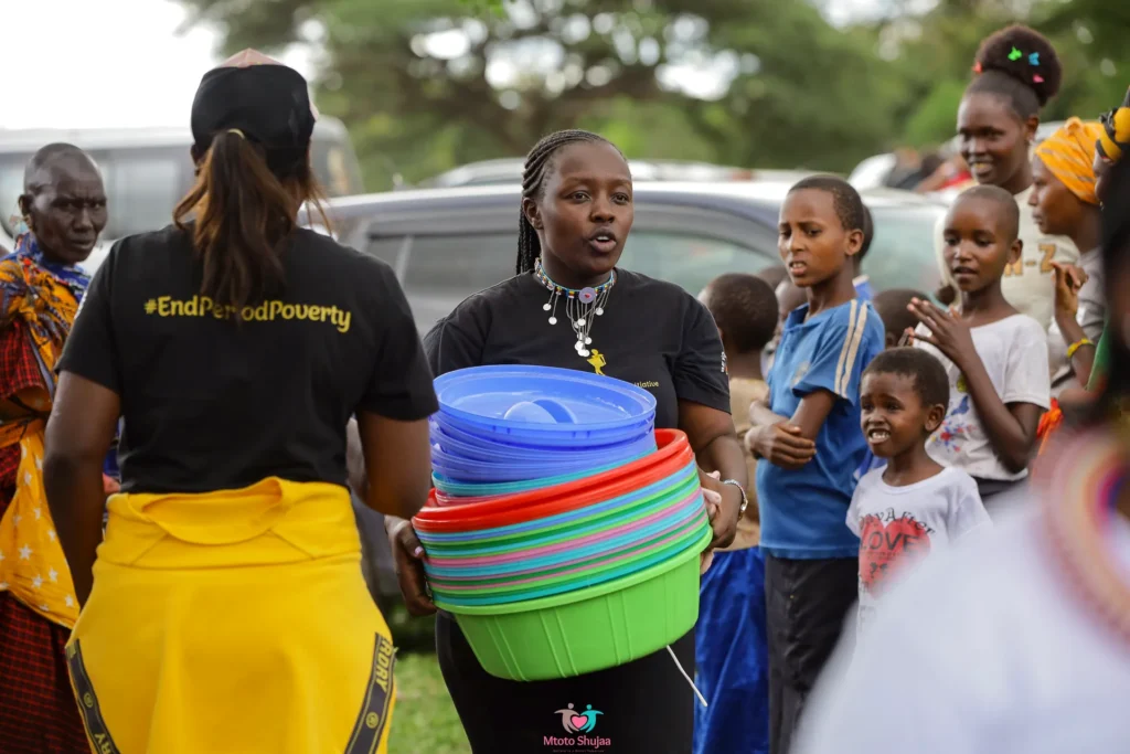 Volunteers in #EndPeriodPoverty T-shirts hand out coloured basins to girls at a community event in Kenya