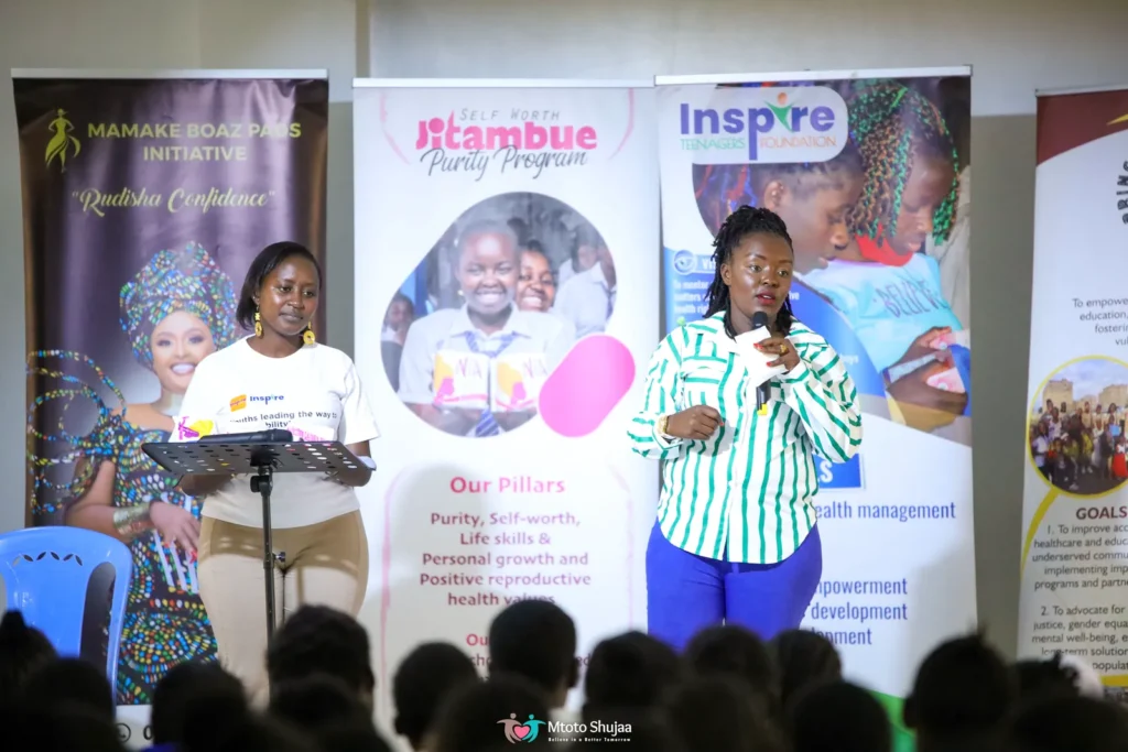 Speakers address a family forum in front of programme banners at a Mtoto Shujaa event in Kenya