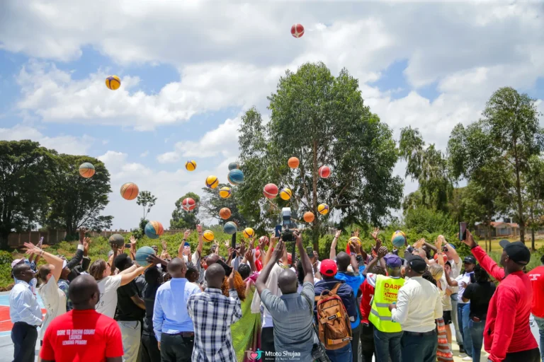 A crowd of students tosses balls into the air on a school field in Kenya